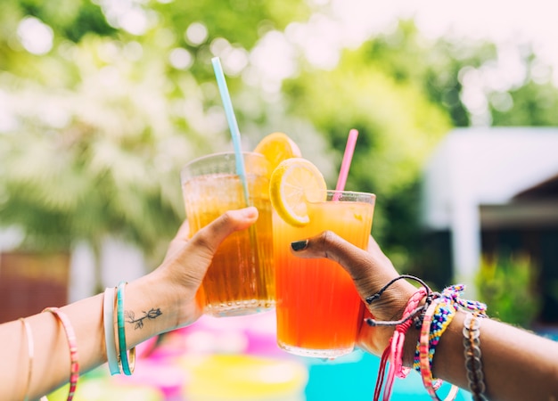 Handen juichen cocktail sap op het zwembad feestje toe