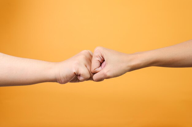 Handen kloppen met de vuist op een gele achtergrond Geste van respect of goedkeuring