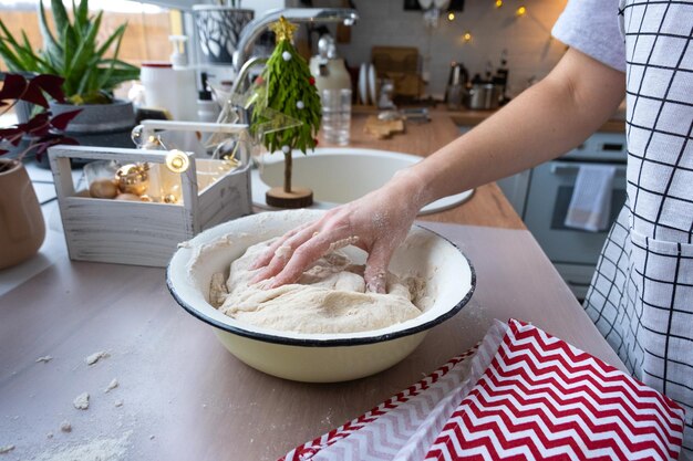 Handen kneden dik deeg op de keukentafel versierd met feestelijke decoraties voor Kerstmis en Nieuwjaar Bakken thuis aroma en comfort Close-up