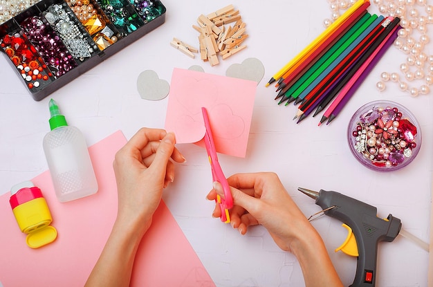 Handen knippen een hart uit roze papier Valentijnsdag ambacht