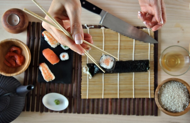 Handen koken sushi met rijst, zalm en nori