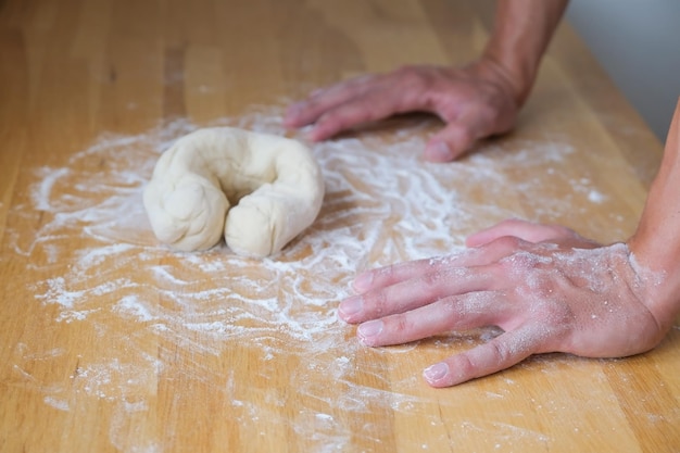 Handen leunen op tafel voor het deeg in bagelvorm