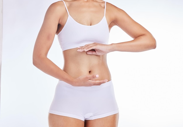 Handen lichaam en gezondheid met een model vrouw frame haar buik in de studio op een grijze achtergrond voor wellness Gewichtsverlies buik en dieet met een vrouw poseren om gezond eten of voeding te bevorderen