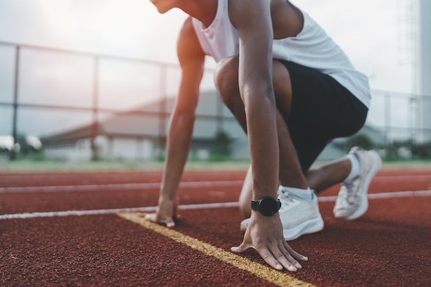 Handen loper klaar om te rennen atleet sportman training rennen op baan in het stadion in de ochtend runner man met wit vest om te oefenen met hardlopen bereid je voor op wedstrijdrace