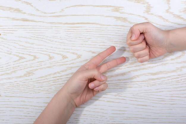 Handen maken rock paper schaar gebaar op houten achtergrond