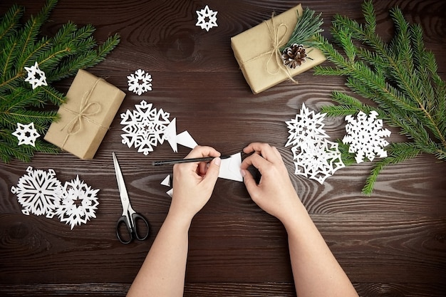 Handen maken van Witboek sneeuwvlokken op houten tafel