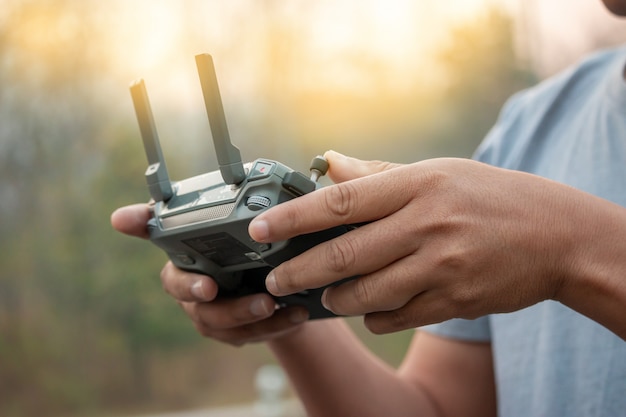 Handen met afstandsbediening van drone buiten.