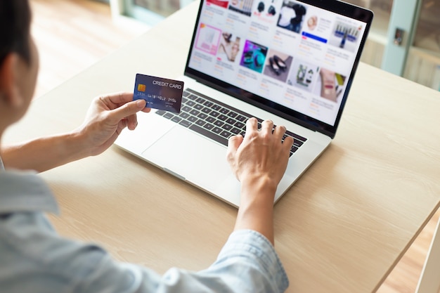 Handen met behulp van een laptop en een creditcard voor online betaling