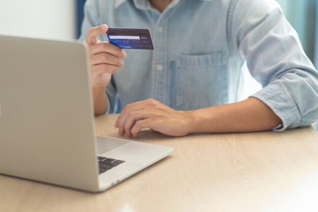 Handen met behulp van een laptop en een creditcard voor online betaling