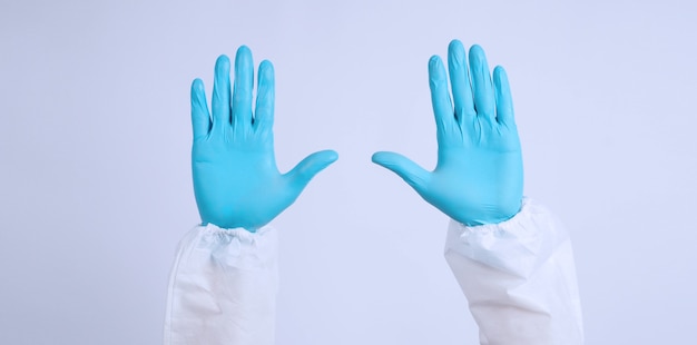 Foto handen met blauwe handschoenen en ppe suite op witte achtergrond.