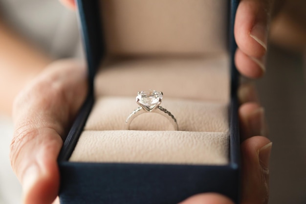 Handen met diamanten ring in juwelendoos