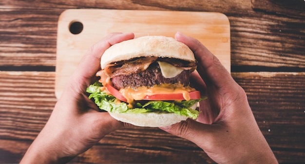 Handen met een kant-en-klare hamburger in restaurant