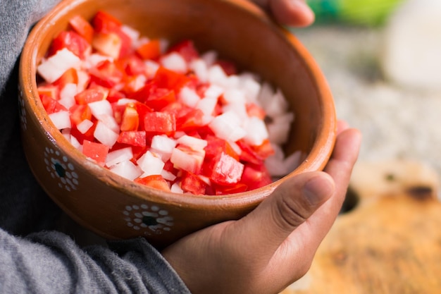 handen met een kom tomatensalade met ui