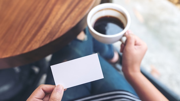 Handen met een lege visitekaartje en een koffiekopje