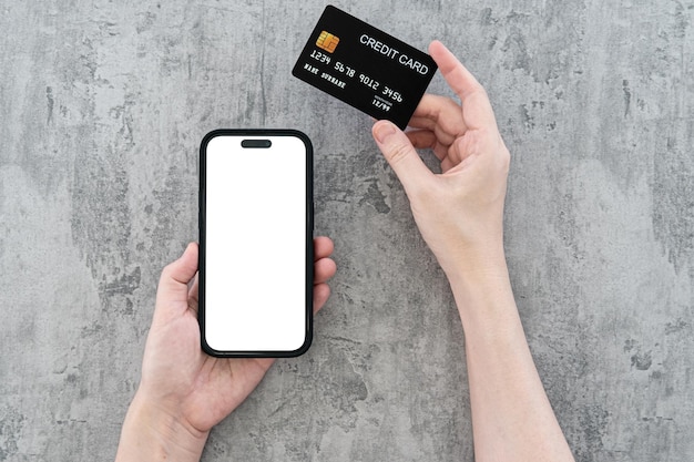 handen met een mobiele telefoon en een creditcard met een leeg scherm