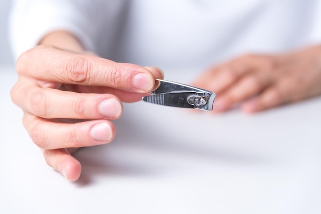 Handen met een nagelknipper vooraan