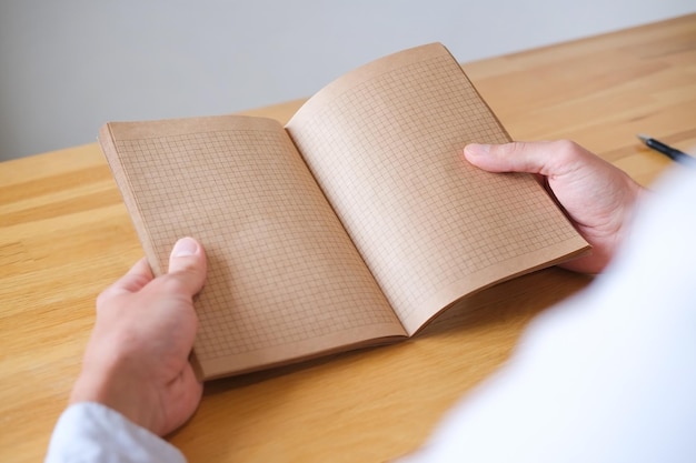 Handen met een open notitieboekje op tafel