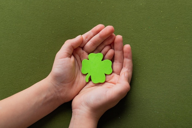 Handen met een shamrock op groene achtergrond Een klavertje vier Goed voor geluk of St. Patrick's Day