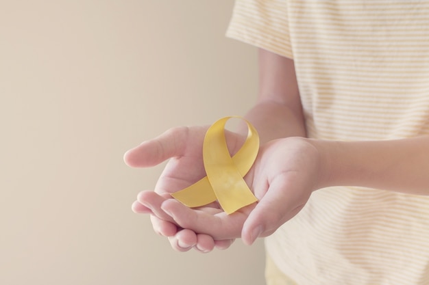 Handen met geel gouden lint, sarcoombewustzijn, bewustzijn van kanker bij kinderen, concept van de Wereld Zelfmoordpreventie Dag