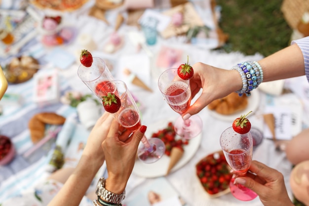 Handen met glazen proost op de picknick van de zomerdag.