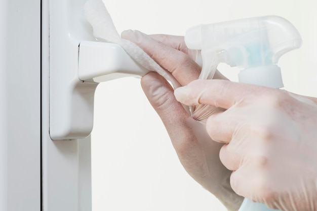 Foto handen met handschoenen die raamgreep ontsmetten