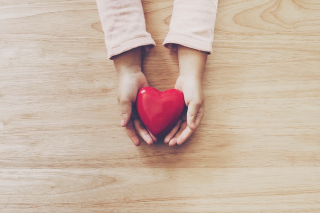 handen met hart op houten tafel achtergrond