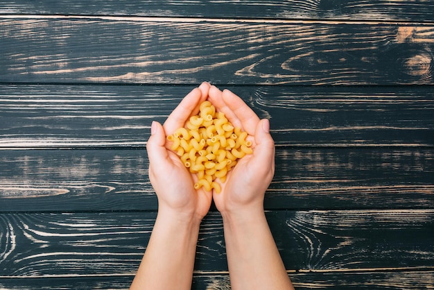 Handen met macaroni Pasta in vrouwelijke handen