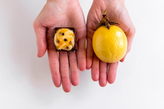 Handen met maracuja snoep en gele passievrucht op witte achtergrond