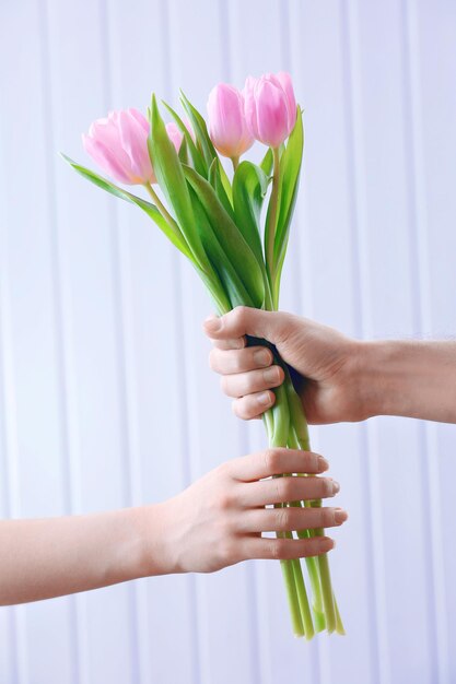 Handen met mooie roze tulpen op houten achtergrond