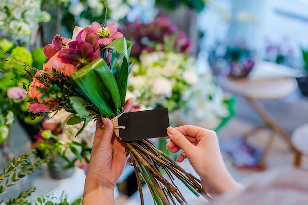 Handen met ontwerpruimte lege kaart met bloemen boeket