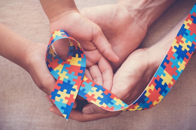 Handen met puzzel lint voor autisme bewustzijn