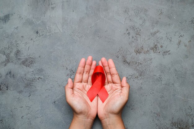 Handen met rood lint, hiv-bewustzijnsconcept, wereldaidsdag, wereldhypertensiedag