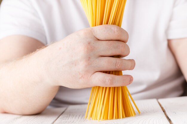 Handen met spaghetti in de keuken