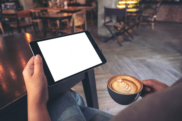 Handen met tablet met leeg scherm tijdens het drinken van koffie