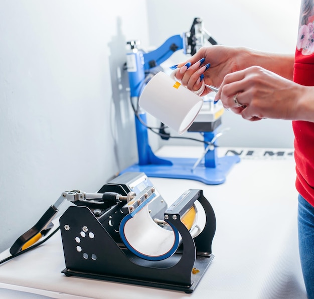 Handen met witte kop mock-up die de afbeelding in een thermopress toepassen