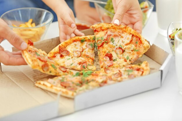 Handen nemen pizza uit tafel close-up