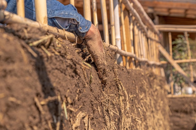 Handen op een lemen muur van een Latino man bioconstructietechniek