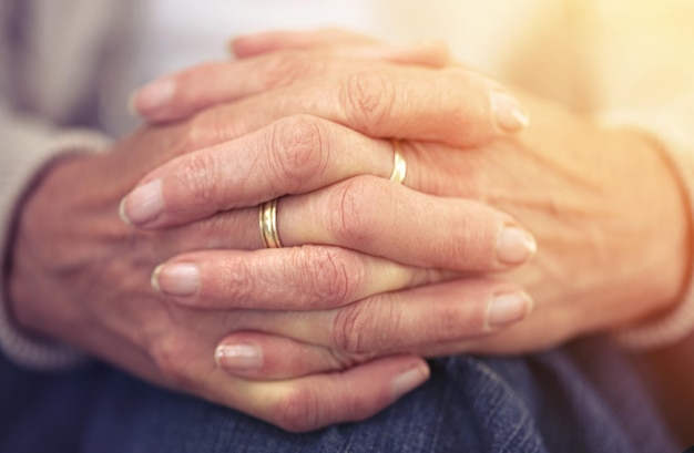 Handen pensioen en nostalgie met een oudere vrouw close-up binnenshuis denkend aan een herinnering uit het verleden Vingers rimpels en ouderdom met een volwassen vrouwelijke gepensioneerde die in haar huis zit en zich eenzaam voelt