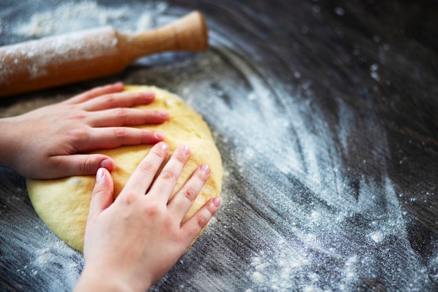 Handen rollingpin en deeg voor brood pasta of pizza op houten tafel