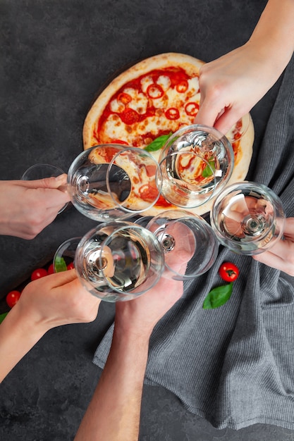 Handen samen met glazen witte wijn op achtergrondpizza