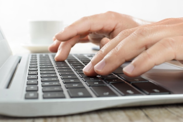 Handen schrijven op een laptop toetsenbord op kantoor in close-up