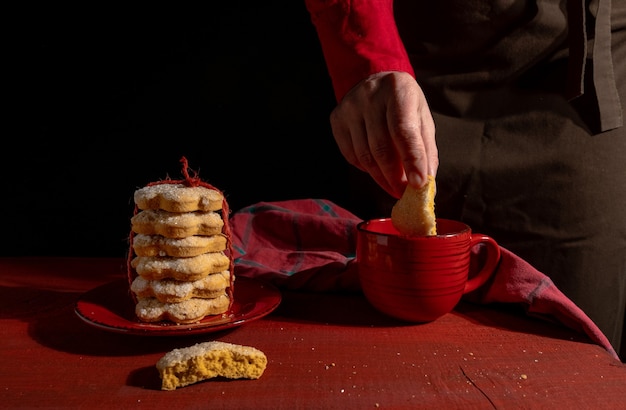 Handen, set van koekjes, rode kopje koffie of thee op rode houten tafel op de zwarte.