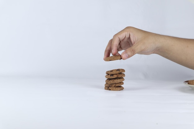 handen stapelen cookies op een witte achtergrond. Menselijke hand die haverkoekje van een stapel neemt