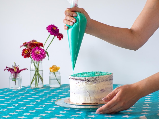 Handen strijken de room glad met een spuitzak en bedekken de ronde cake