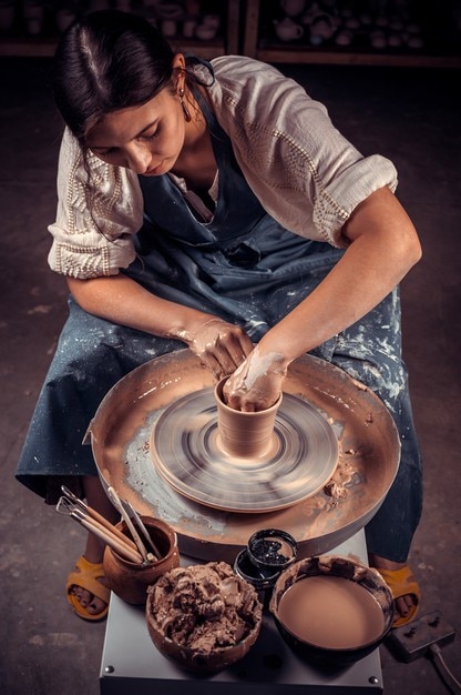 Handen van ambachten-kunstenaar maken van ambacht, aardewerk, beeldhouwer van verse natte klei op pottenbakkersschijf, modelleren van aardewerk op de pottenbakkersschijf