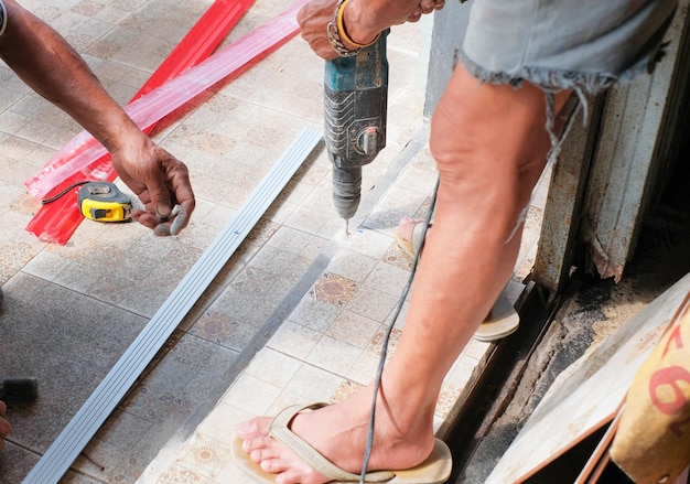 handen van arbeider die elektrische boor houdt die aluminium hout boort op de bouwplaats