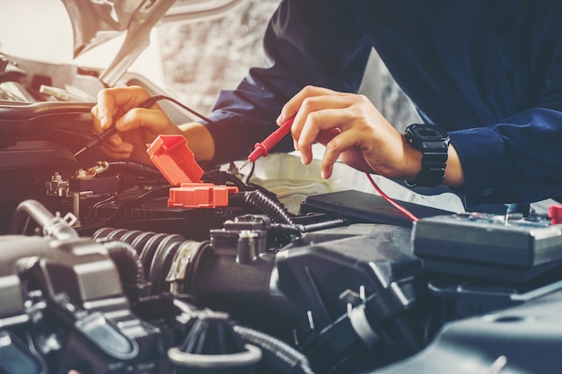 Handen van automonteur die in de autoreparatiedienst werken.