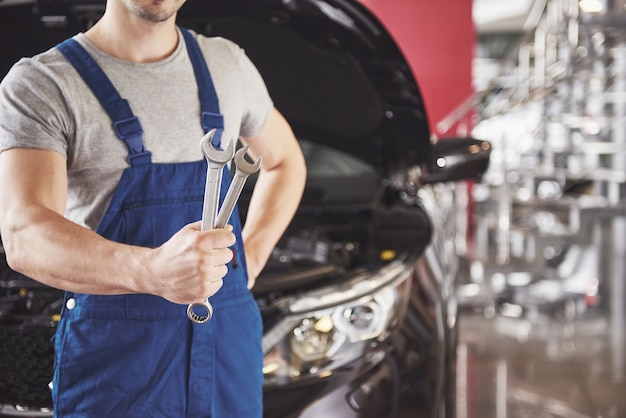 Handen van automonteur met moersleutel in garage.