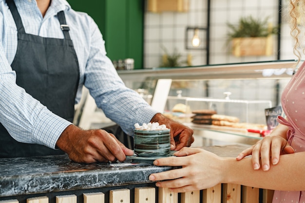 Handen van barista serveren een kopje warme chocolademelk drinken versierd met marshmellows op teller