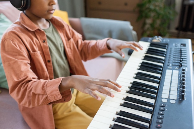 Handen van biraciale schooljongen over toetsen van muziektoetsenbord